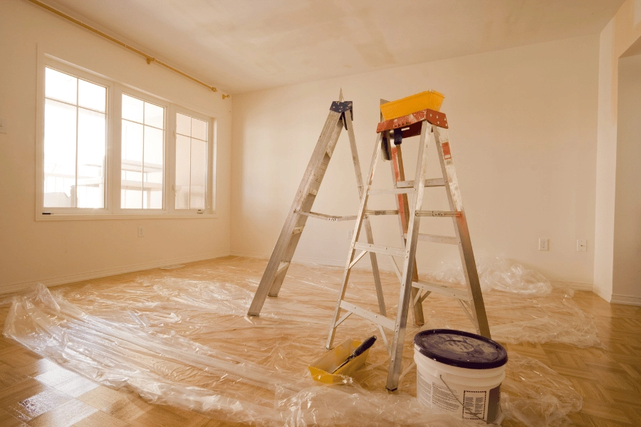 two ladders and a paint bucket inside of a renovated home 